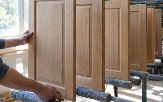 A bare wood cabinet door being cleaned and prepared before the primer goes on.